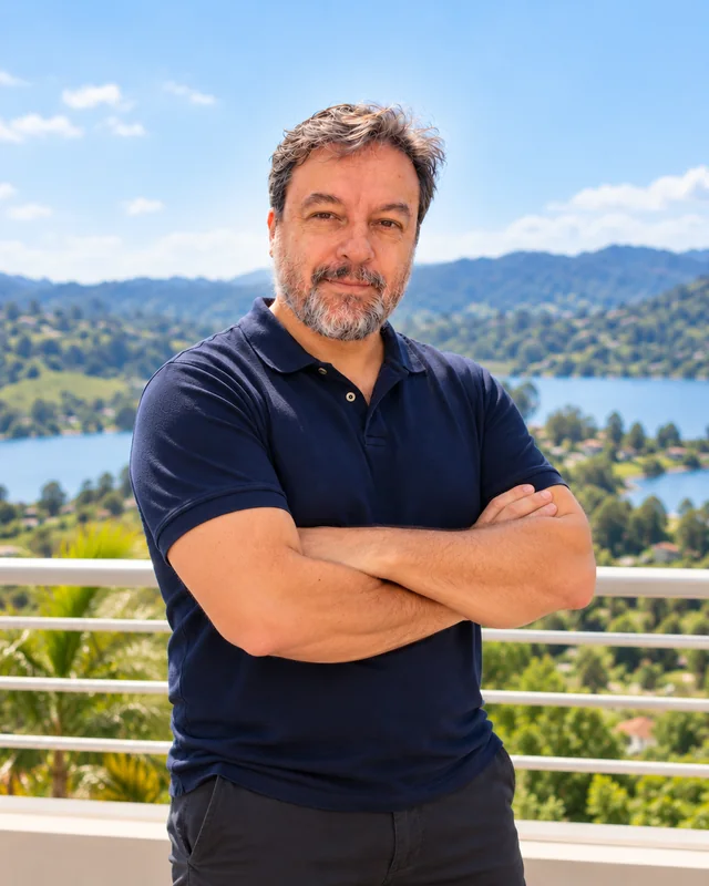 Edmar Daniel de polo azul-marinho e braços cruzados, com a represa ao fundo